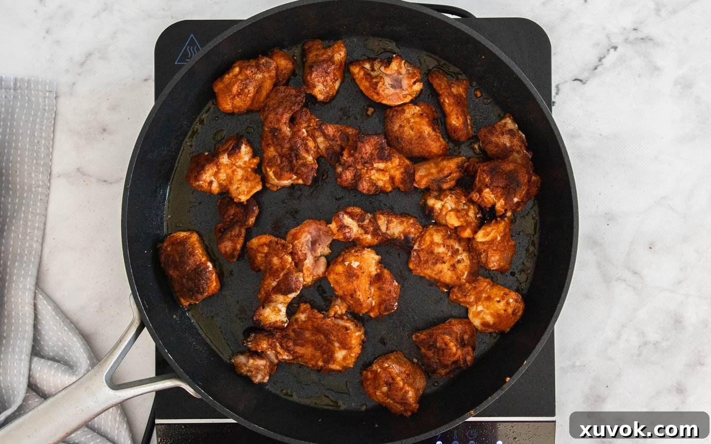 Chicken searing in a hot frying pan to brown the exterior.