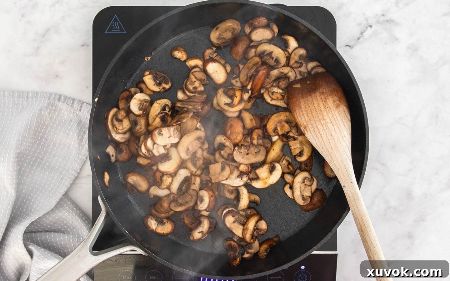 Sliced mushrooms frying in a pan until golden brown.