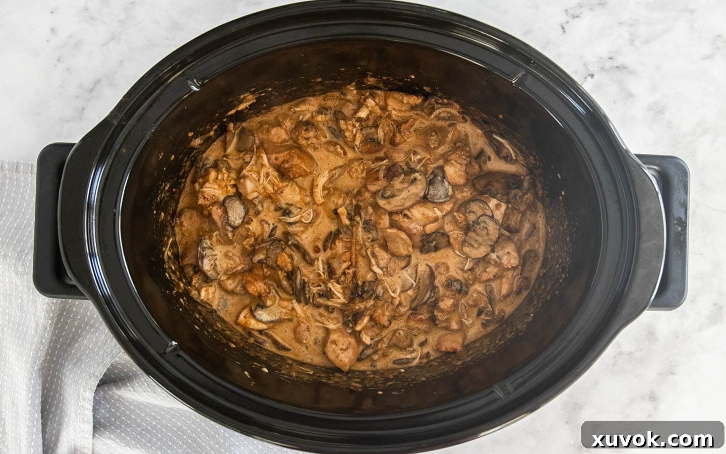 The chicken stroganoff in a slow cooker bowl with the sour cream and mushrooms stirred through, ready to serve.