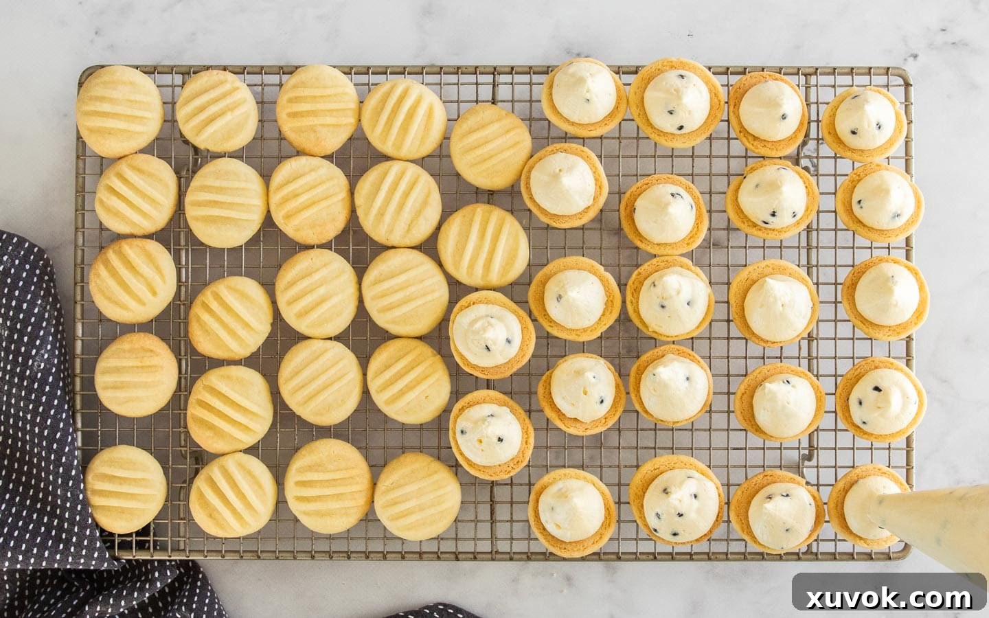 Piping the vibrant passionfruit frosting onto the flat side of a cooled cookie.