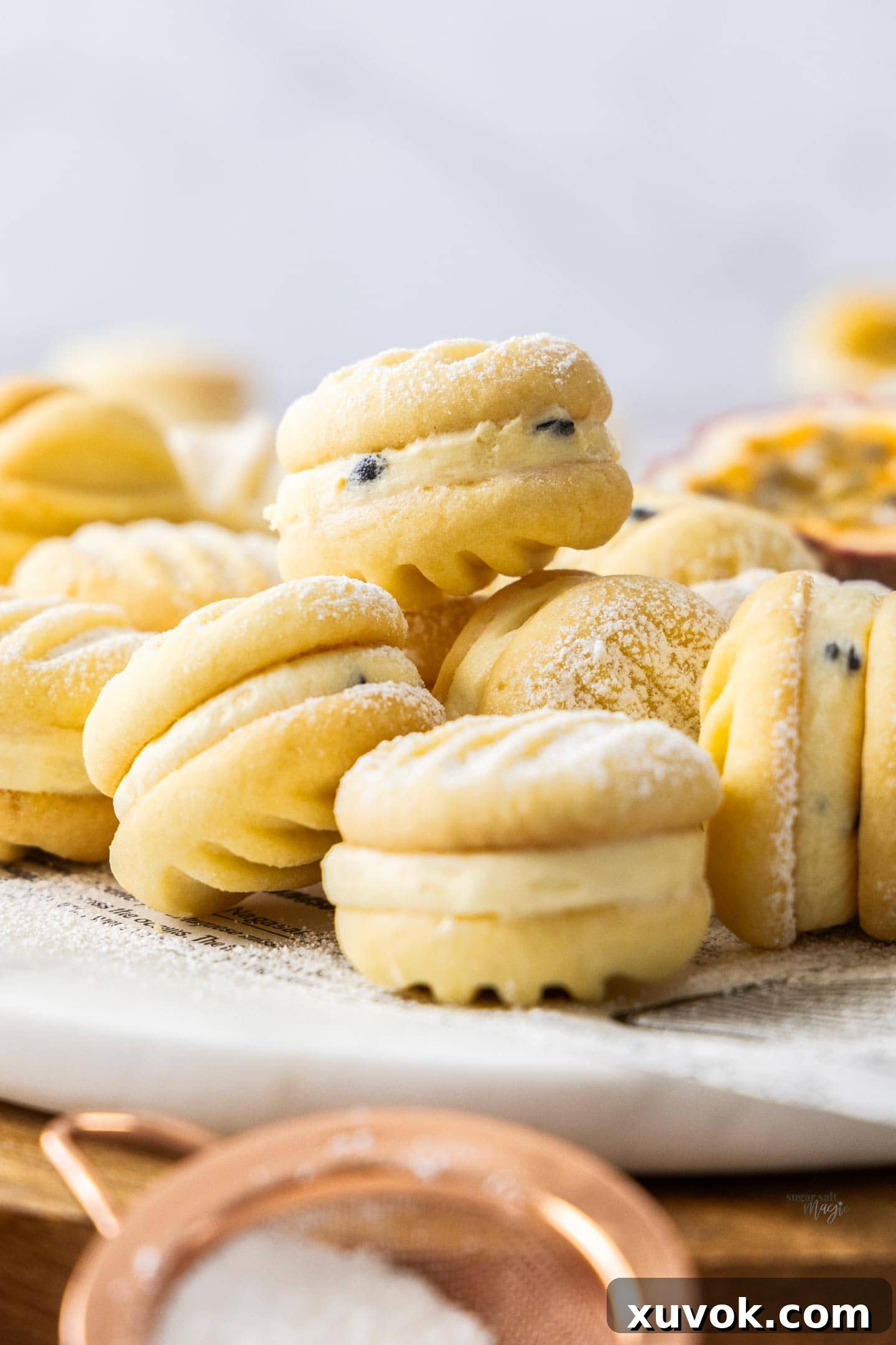 Passionfruit melting moments piled up, showcasing the creamy buttercream filling and delicate cookie texture.
