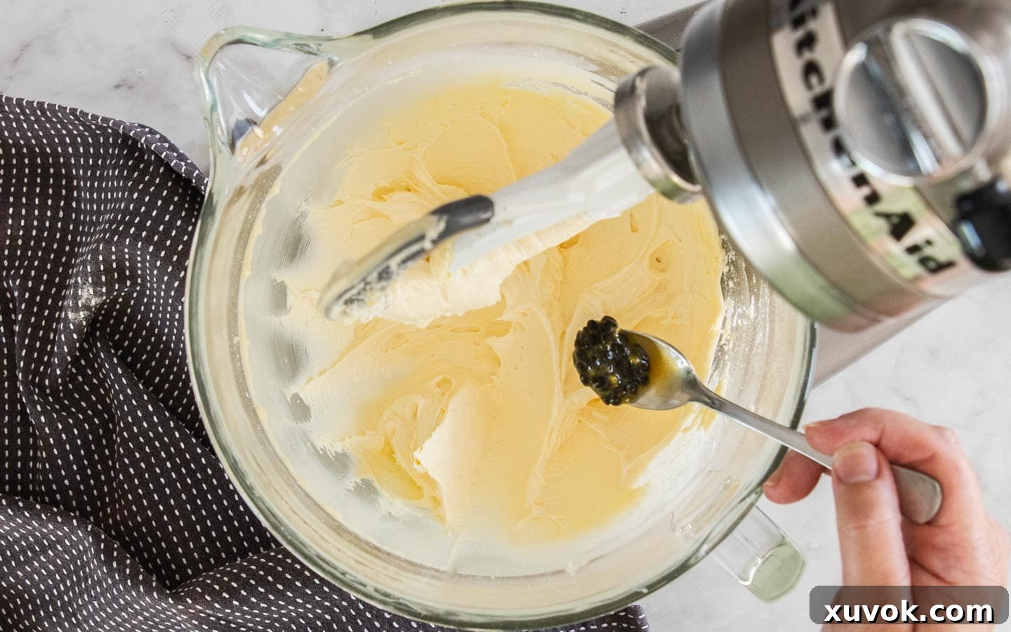 Adding passionfruit seeds to the creamy buttercream mixture.
