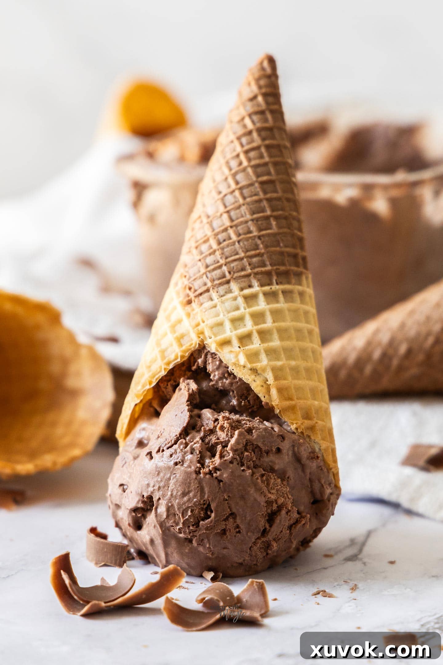 A waffle cone filled with double chocolate ice cream sitting upside down on a marble surface.