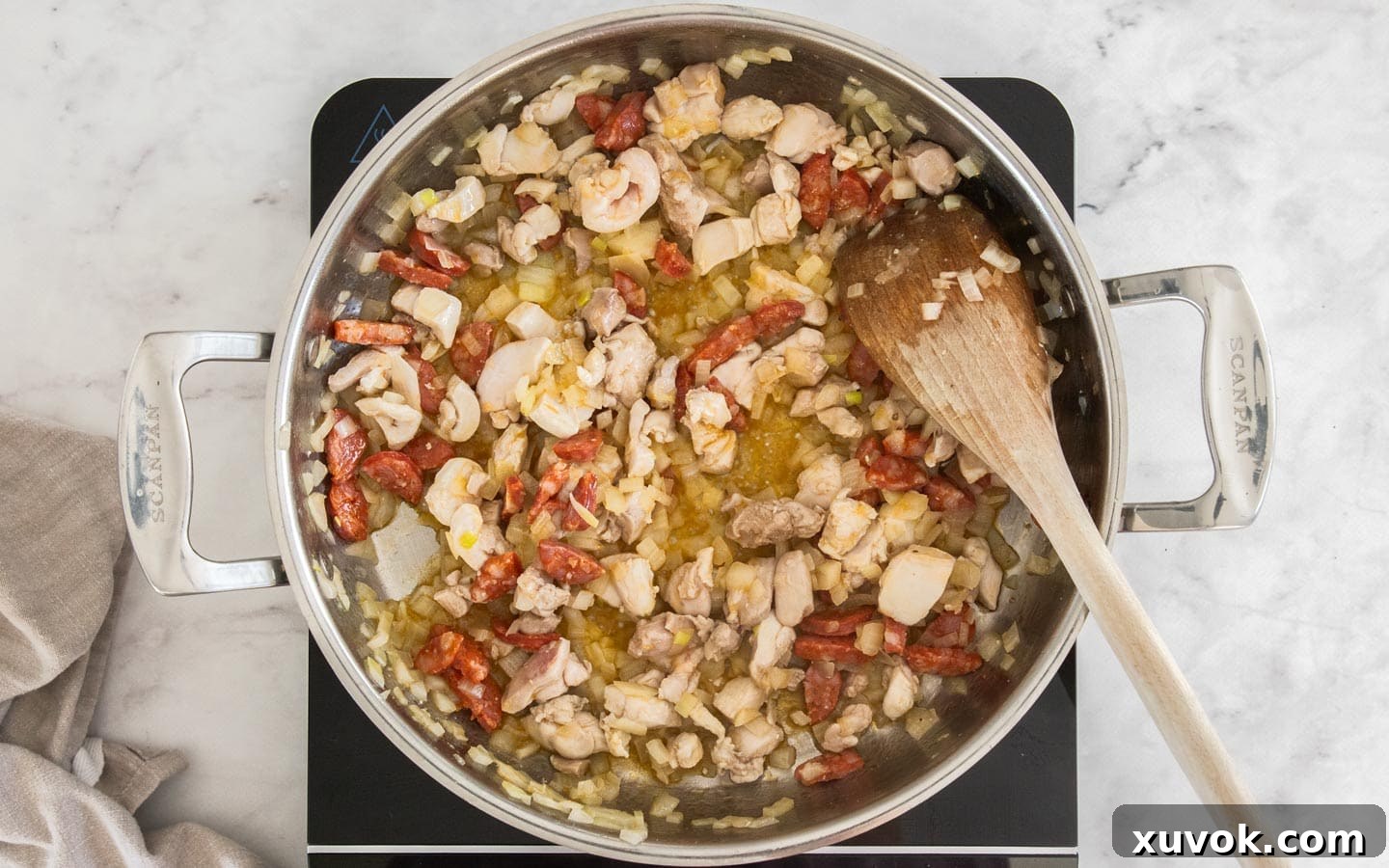 Chicken, onion and chorizo cooking in a pan.