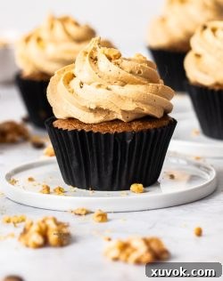 A single coffee and walnut cupcake on a small dessert plate.