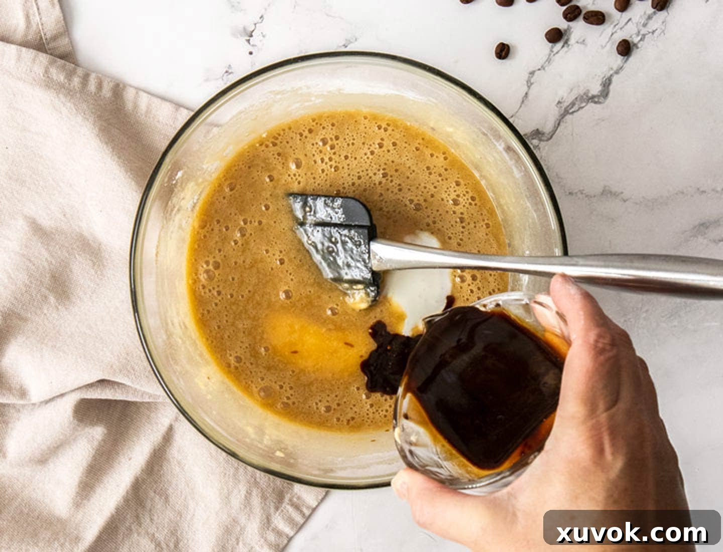 The coffee being added to the wet ingredients in a bowl.