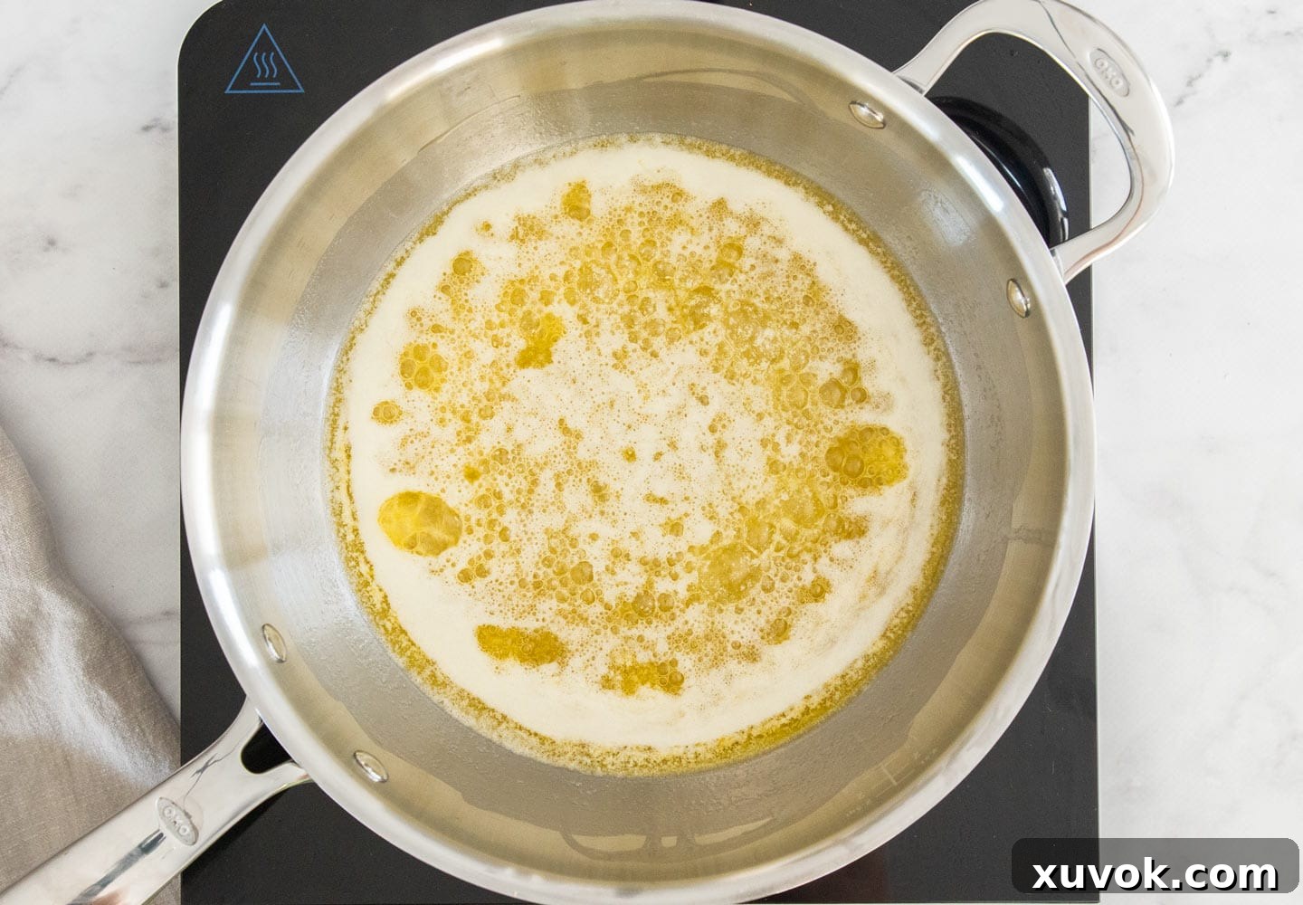 Unsalted butter melting and beginning to foam in a saucepan, the first stage of browning.