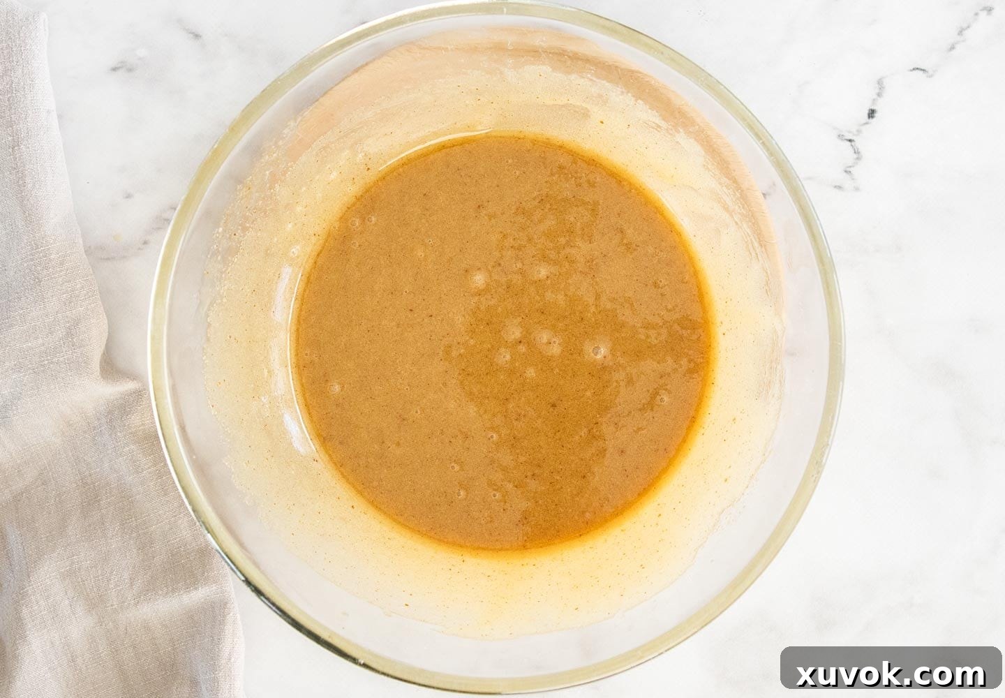 The wet ingredients, including eggs and vanilla, fully combined and whisked in a mixing bowl.
