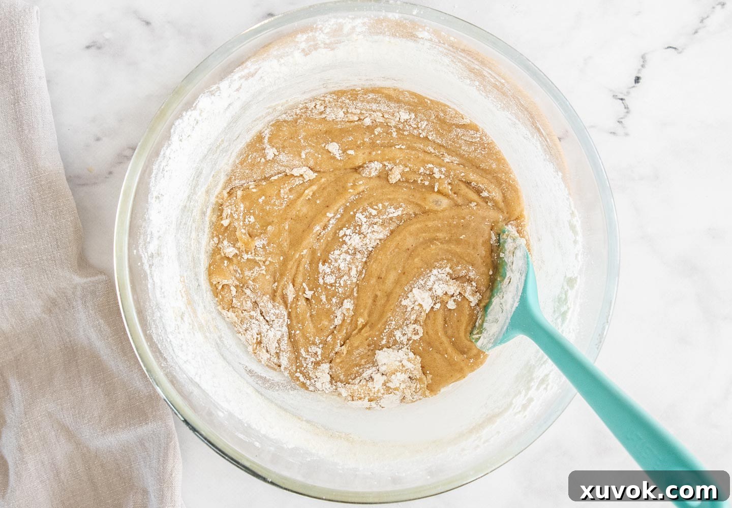 Plain flour and salt partially incorporated into the blondie batter, showing slight streaks of flour.