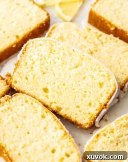 Closeup of a perfectly sliced lemon loaf cake with a generous drizzle of lemon glaze, showcasing its moist interior.