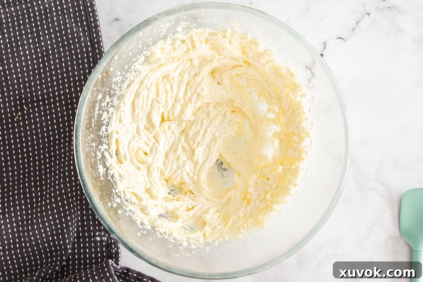 Creamed butter and vegetable oil blended into the lemon sugar mixture, appearing light and fluffy in a mixing bowl.