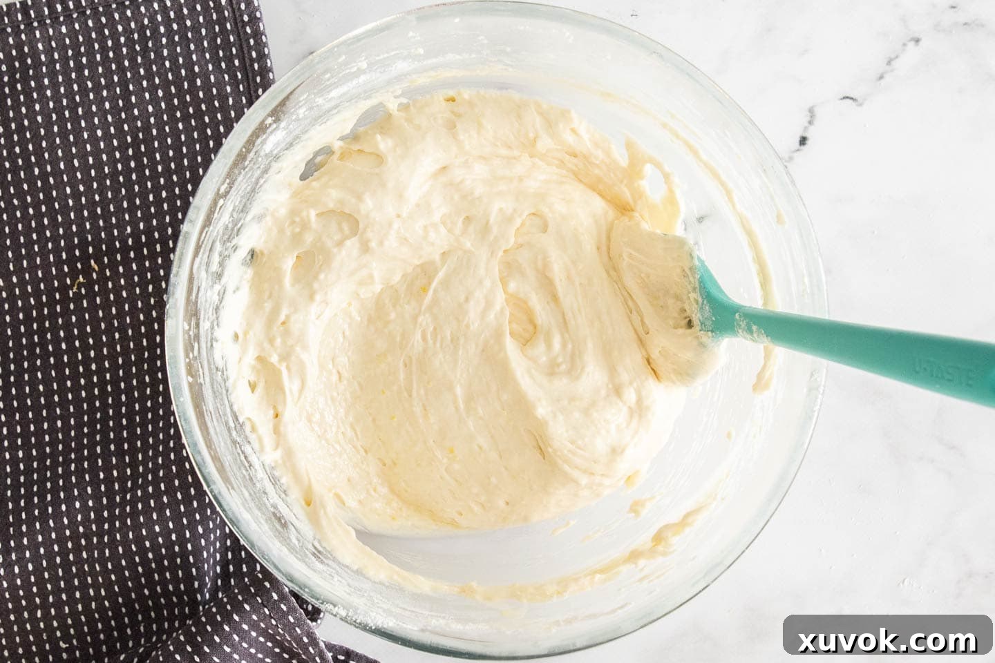 Smooth, pale yellow lemon loaf cake batter filling a mixing bowl, ready for baking.