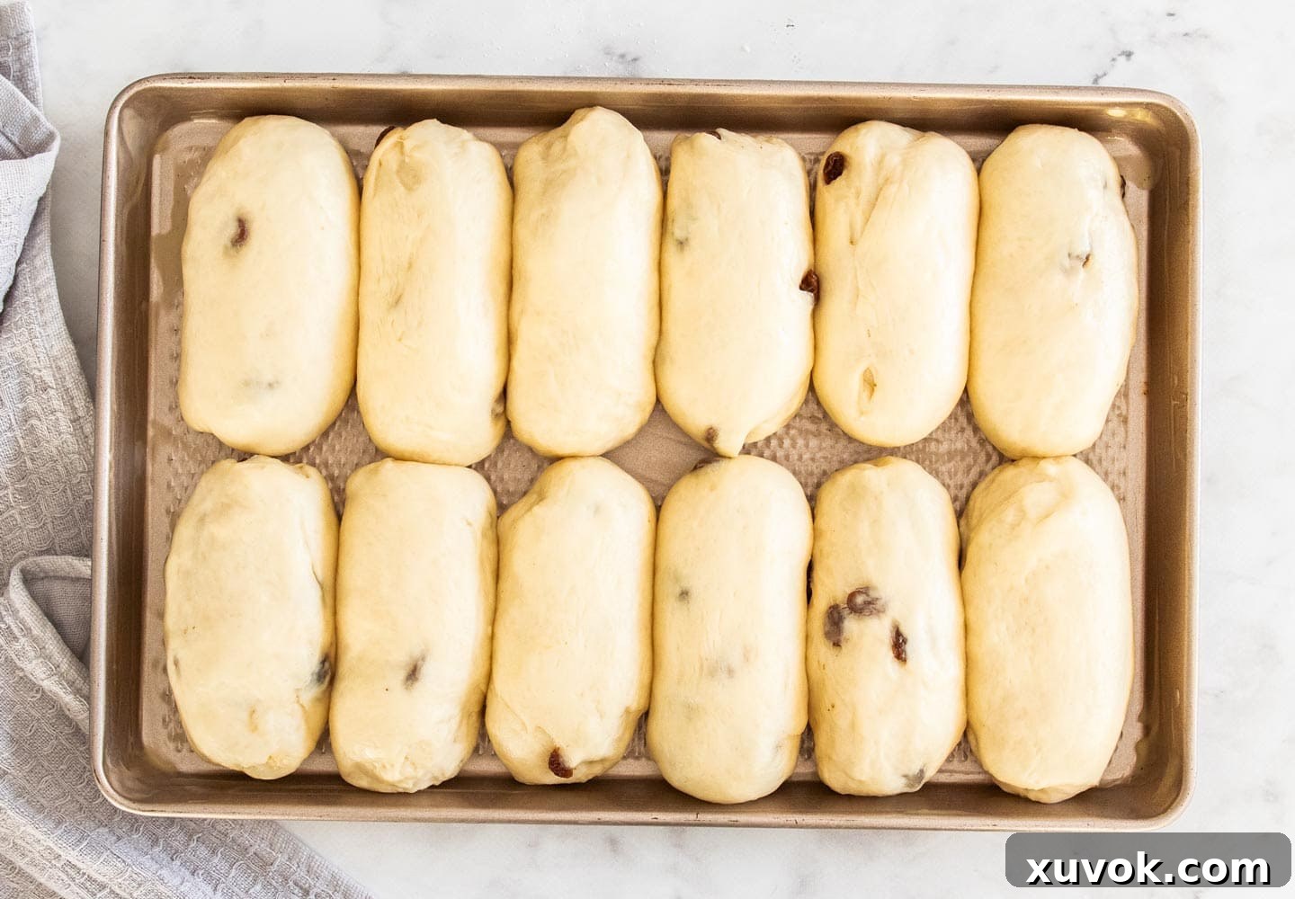 The finger buns after their second prove, noticeably larger and puffier on the baking tray, indicating they are ready for the oven.