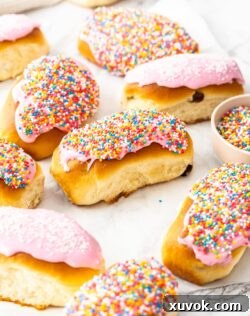 A batch of classic Australian finger buns, baked to golden perfection and topped with luscious icing, arranged on a sheet of baking paper.