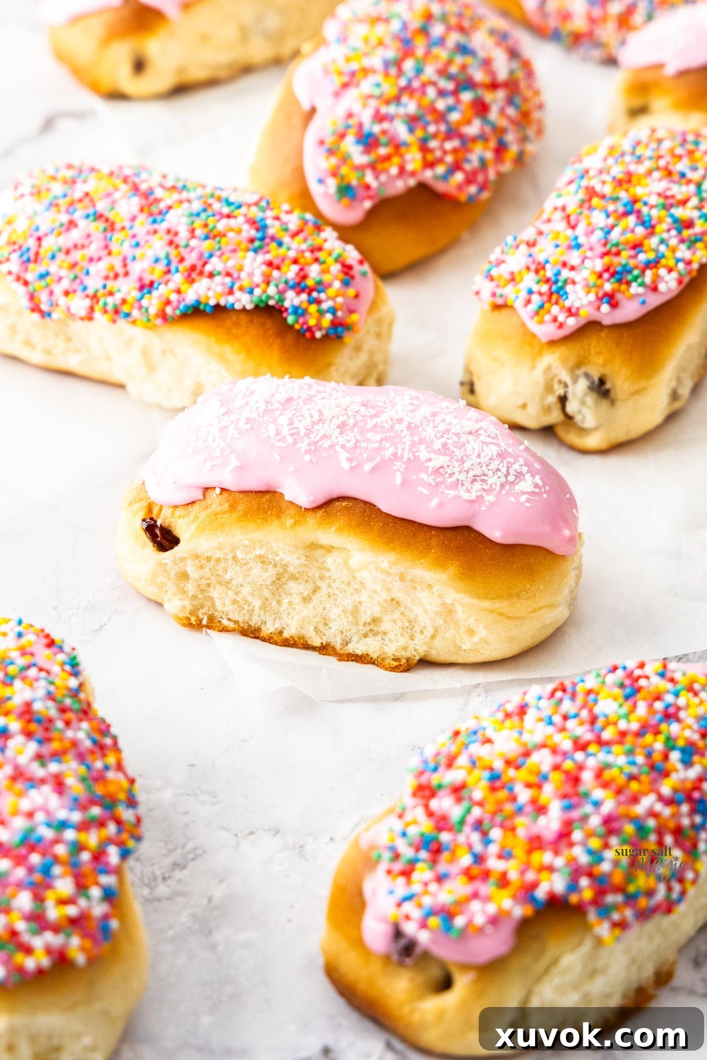 A single perfectly iced finger bun, topped with a delicate layer of shredded coconut, resting on a clean surface, highlighting an alternative classic topping.