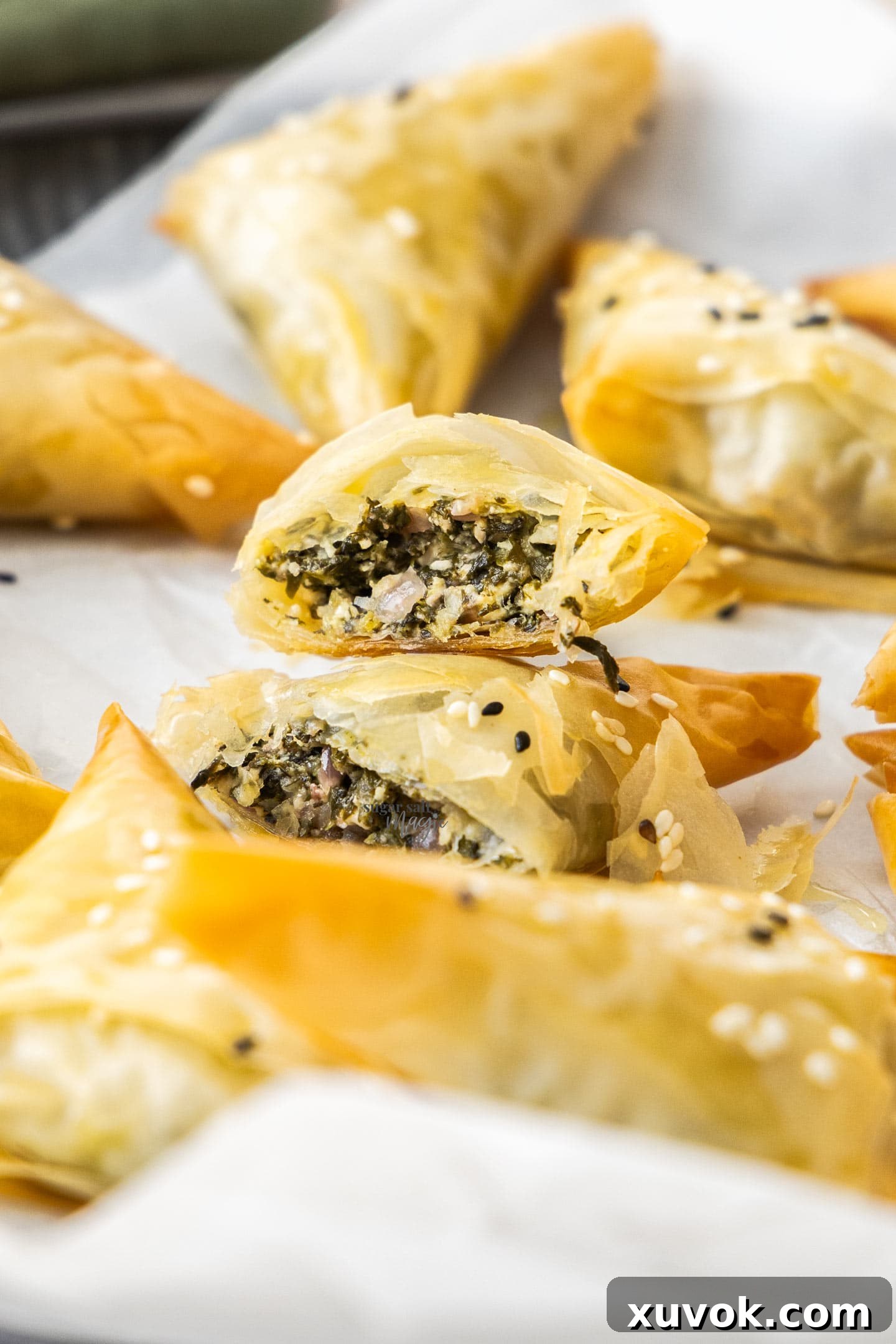 A perfectly baked spinach and feta triangle, cut open to reveal its creamy, vibrant spinach and cheese filling.