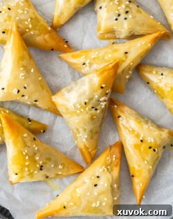 Top down view of a tray of golden-brown spanakopita triangles.