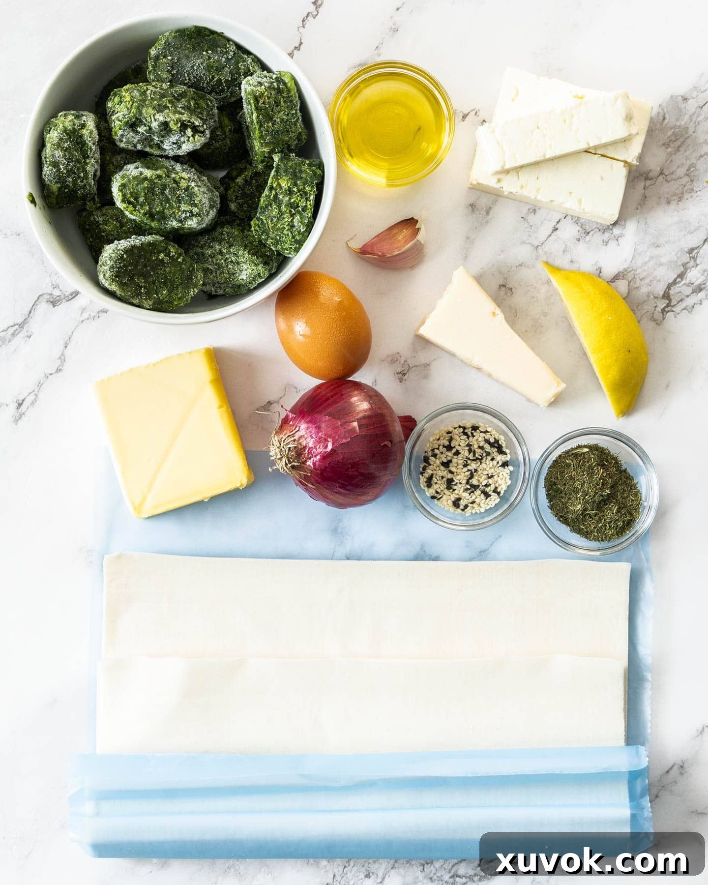 A vibrant collection of ingredients for spinach and feta parcels, including fresh spinach, crumbly feta, and delicate filo pastry.