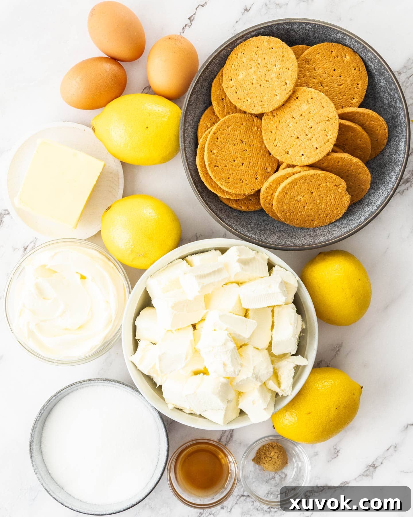 Ingredients for baked lemon cheesecake on a marble surface.