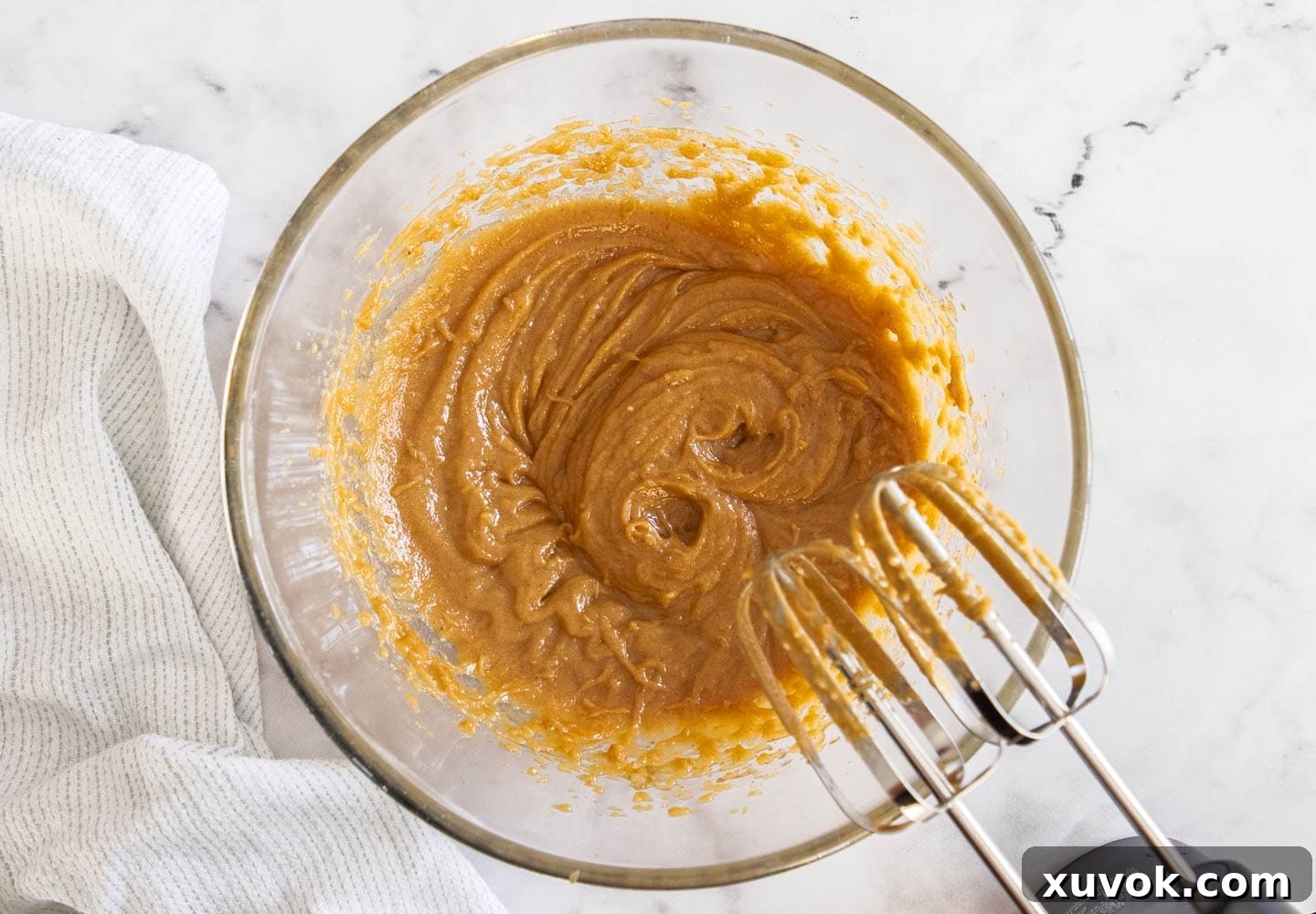 The perfectly combined wet ingredients and sugars in a mixing bowl, showcasing a smooth and creamy texture, ready for the dry components.