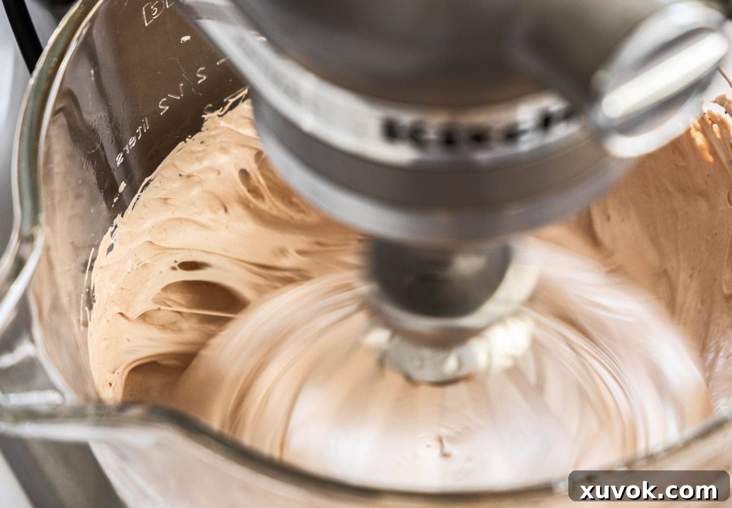 Thick chocolate marshmallow mixture in a mixing bowl, showing sticky strings pulling away from the sides, indicating it's ready.