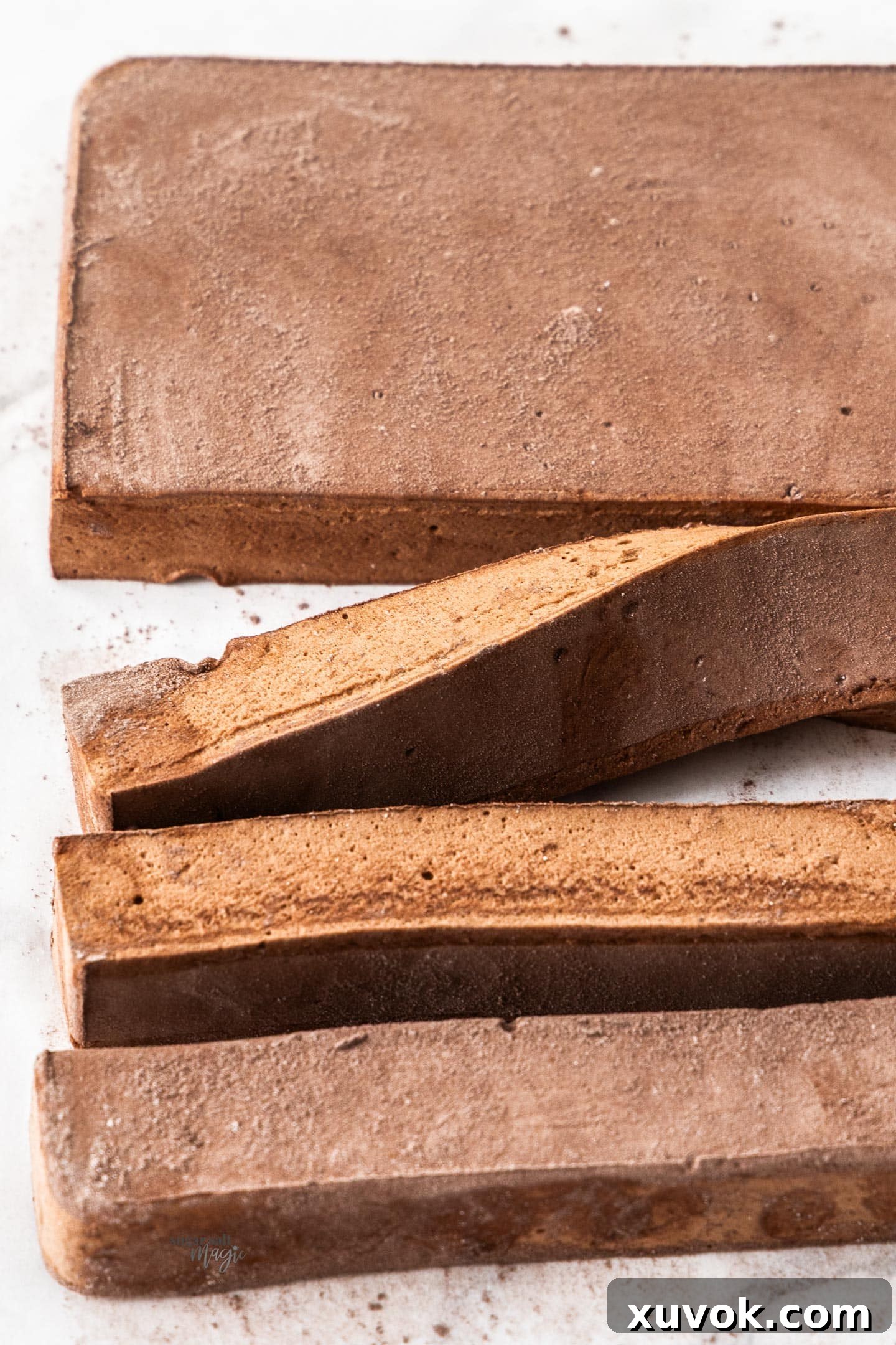 A block of chocolate marshmallow with three strips already cut from it, showing the process of portioning.