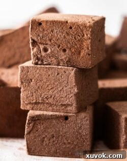 A stack of three fluffy homemade chocolate marshmallows, perfectly dusted.