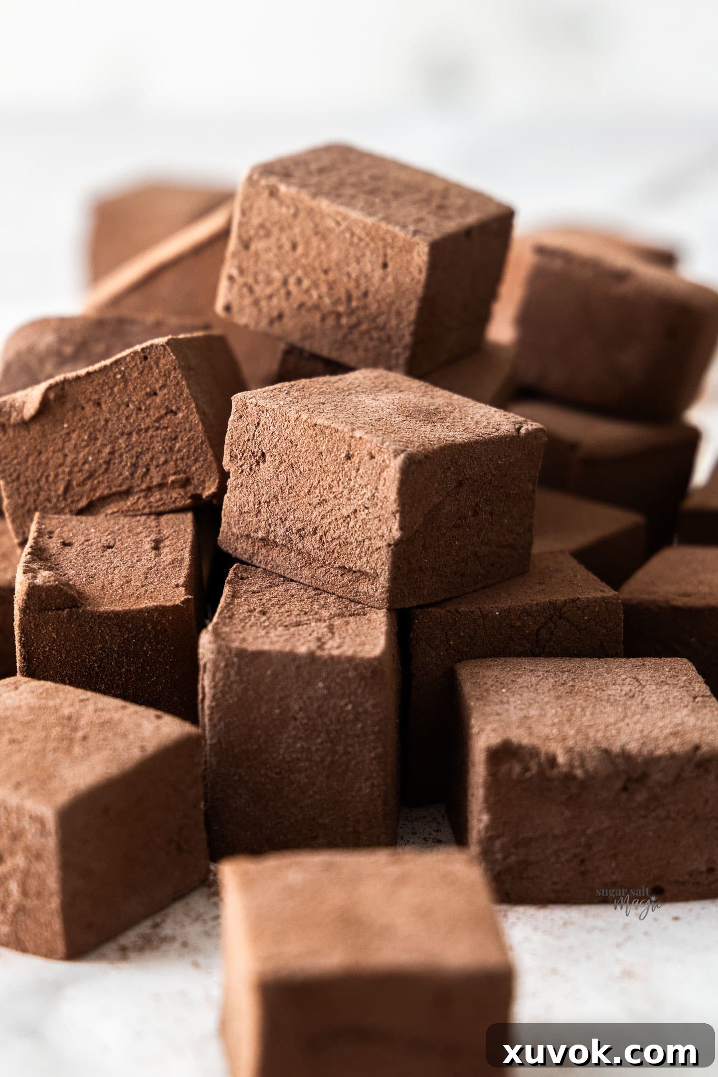 A perfectly arranged pile of square homemade chocolate marshmallows, dusted lightly with cocoa sugar.