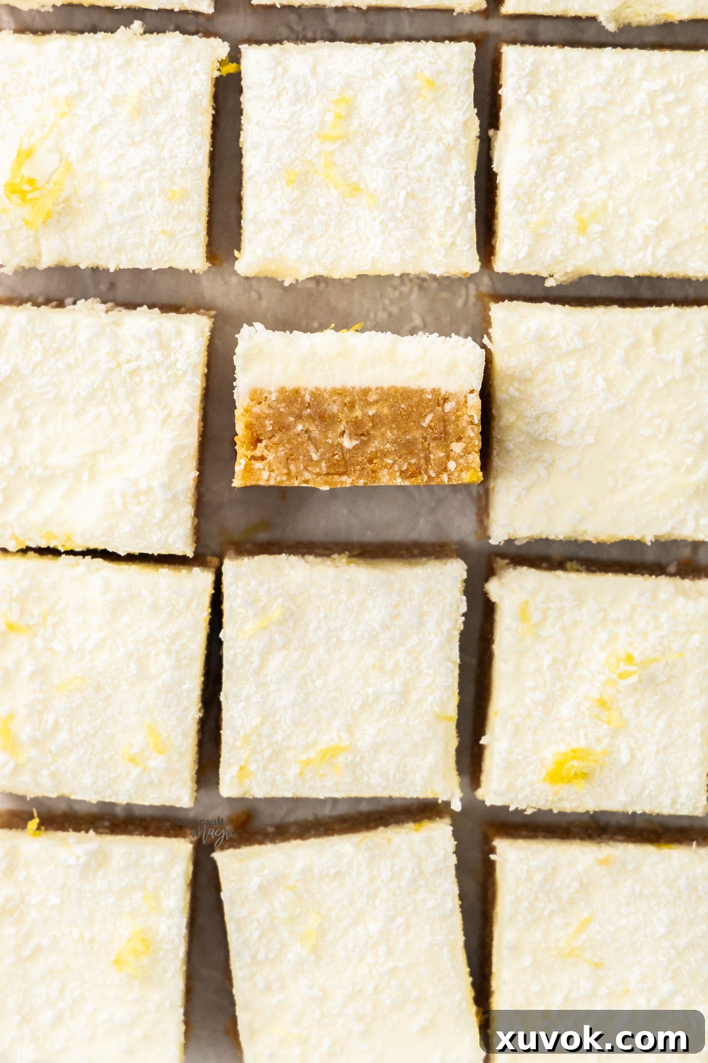 Top down view of 12 squares of lemon coconut slice, showcasing the creamy yellow topping and golden base.