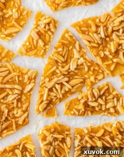Top down view of a batch of almond praline broken into shards.