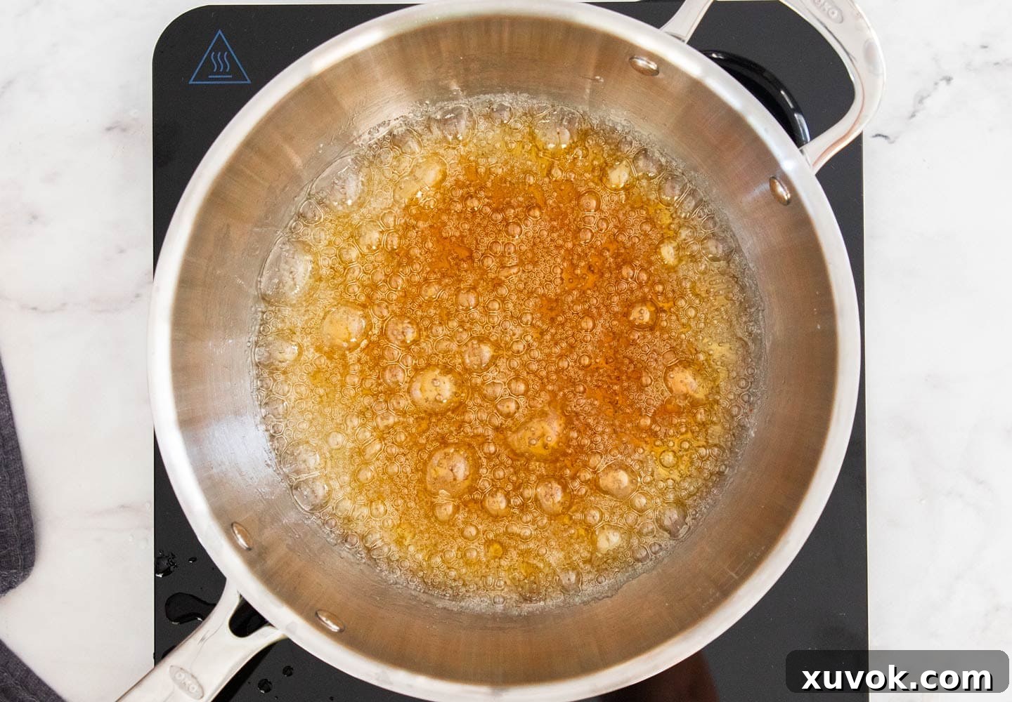 Toffee bubbling and reaching a deep amber color in a pan, indicating it's nearly ready.