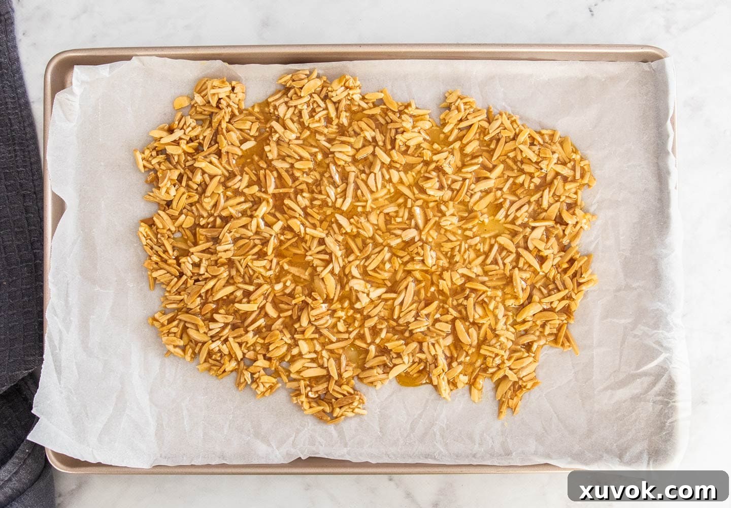 The hot almond toffee mixture spread thinly and evenly on a baking sheet lined with parchment paper.