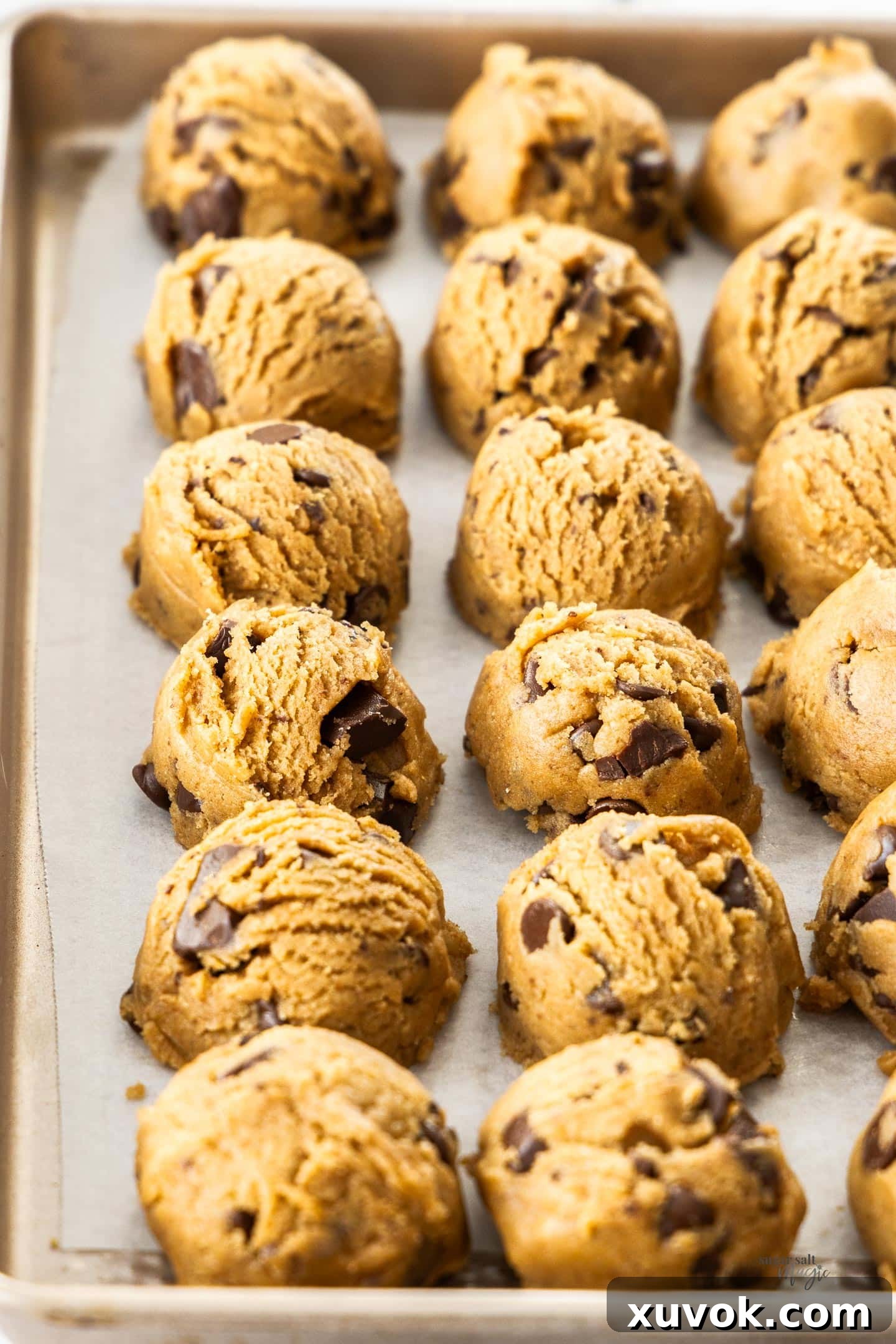 Uniform scoops of chocolate chip cookie dough arranged neatly on a baking pan, ready for chilling and baking.