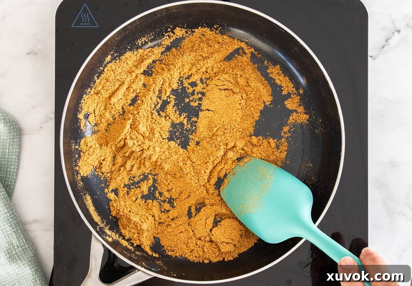 Milk powder being toasted in a non-stick pan, turning a rich golden-brown hue.