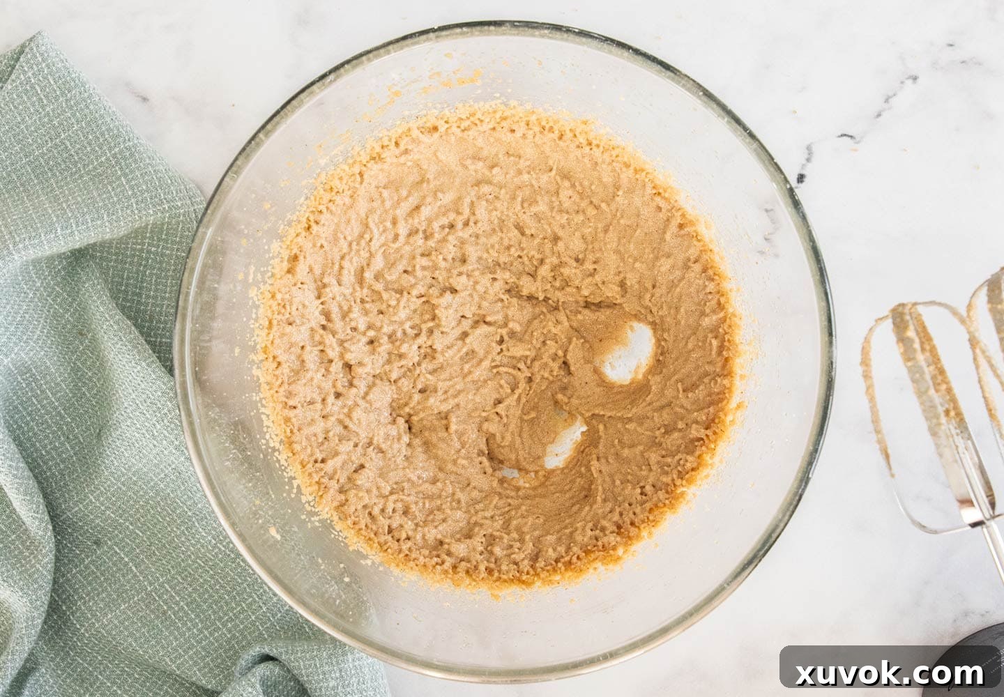 The wet ingredients, including browned butter, sugars, and eggs, beaten together into a creamy, light mixture in a bowl.