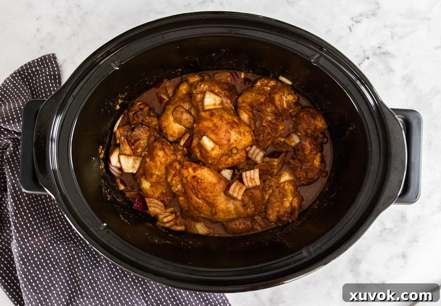 The chicken and onions added to the slow cooker.