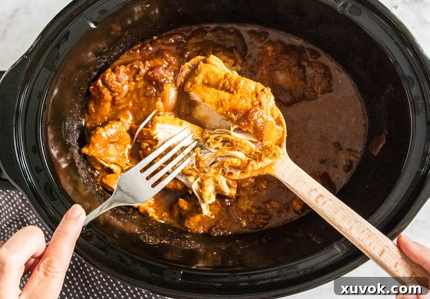 The chicken being broken apart with a fork.