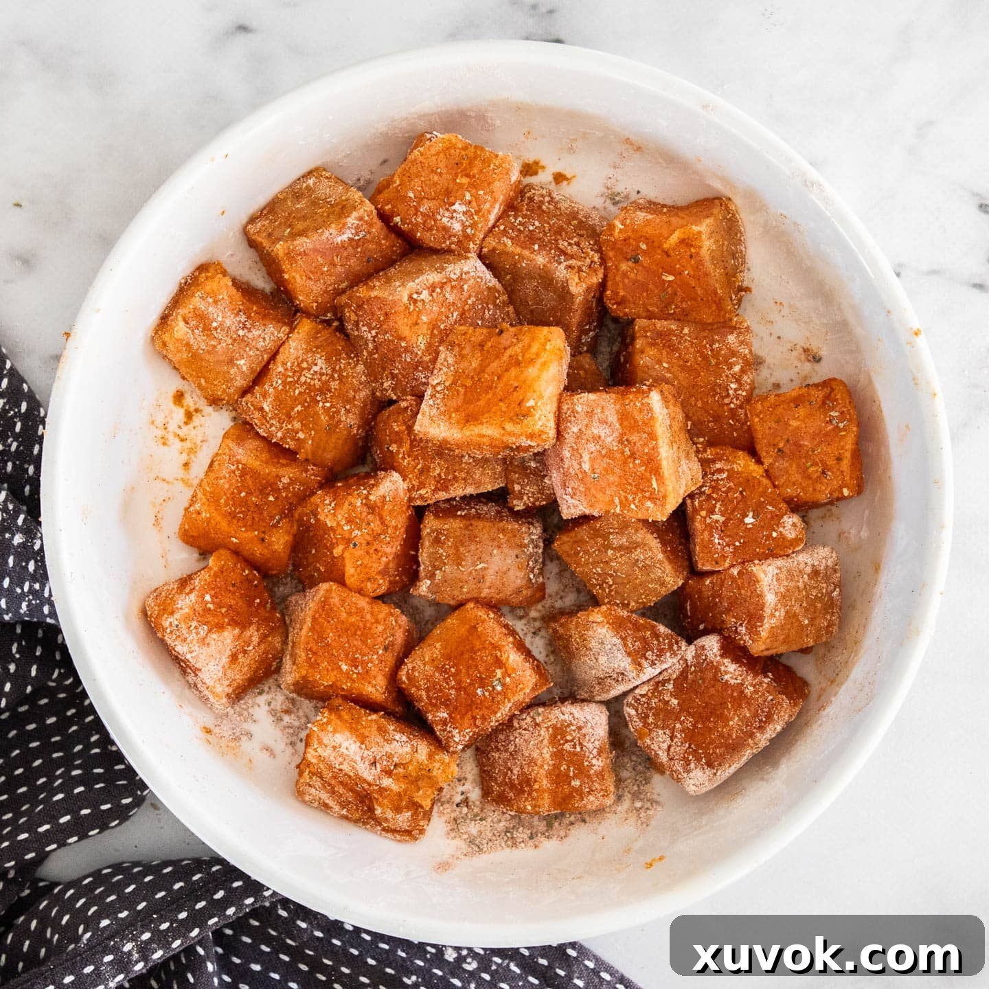 Cubes of salmon dusted with the seasoning in a bowl.