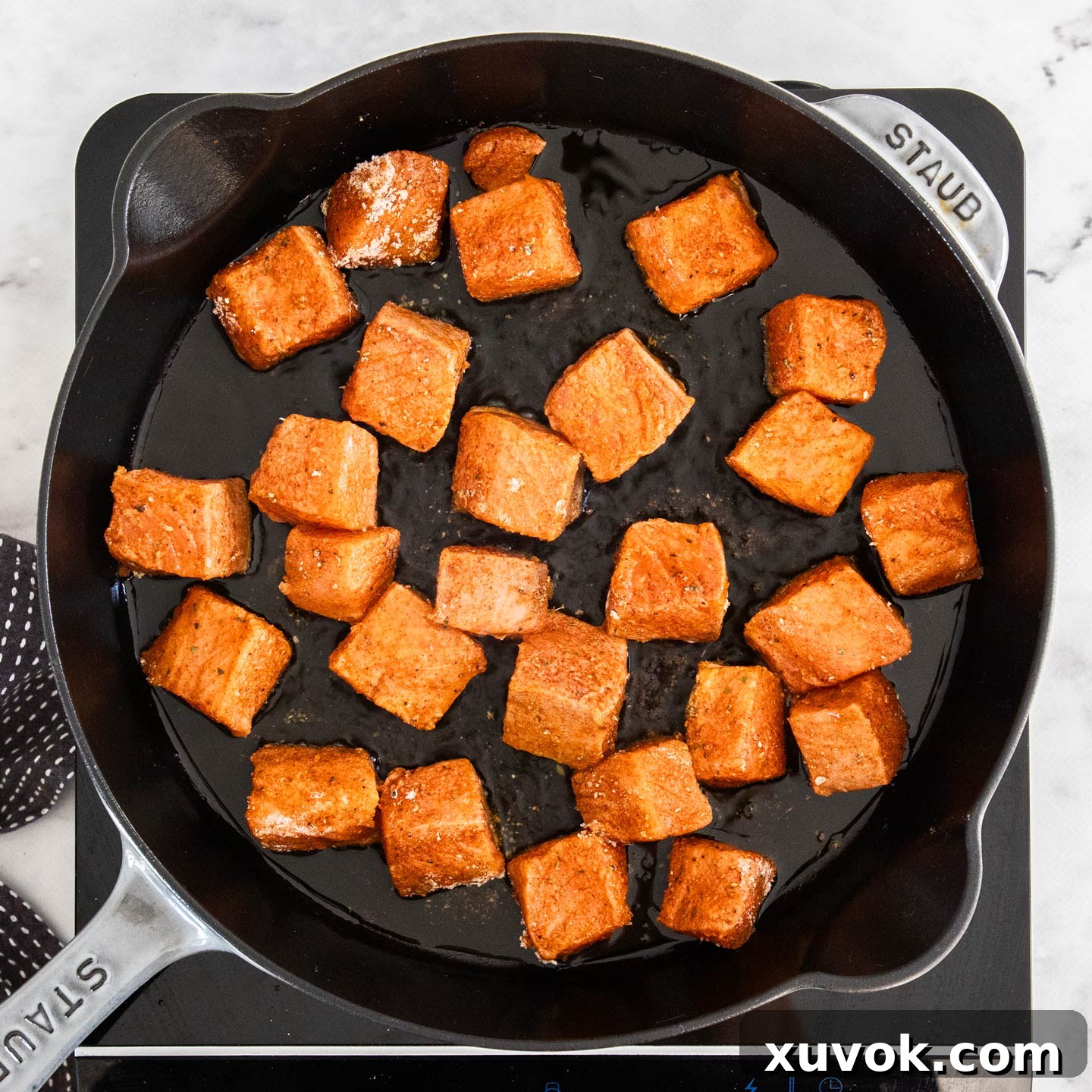 Salmon bites cooking in a pan.
