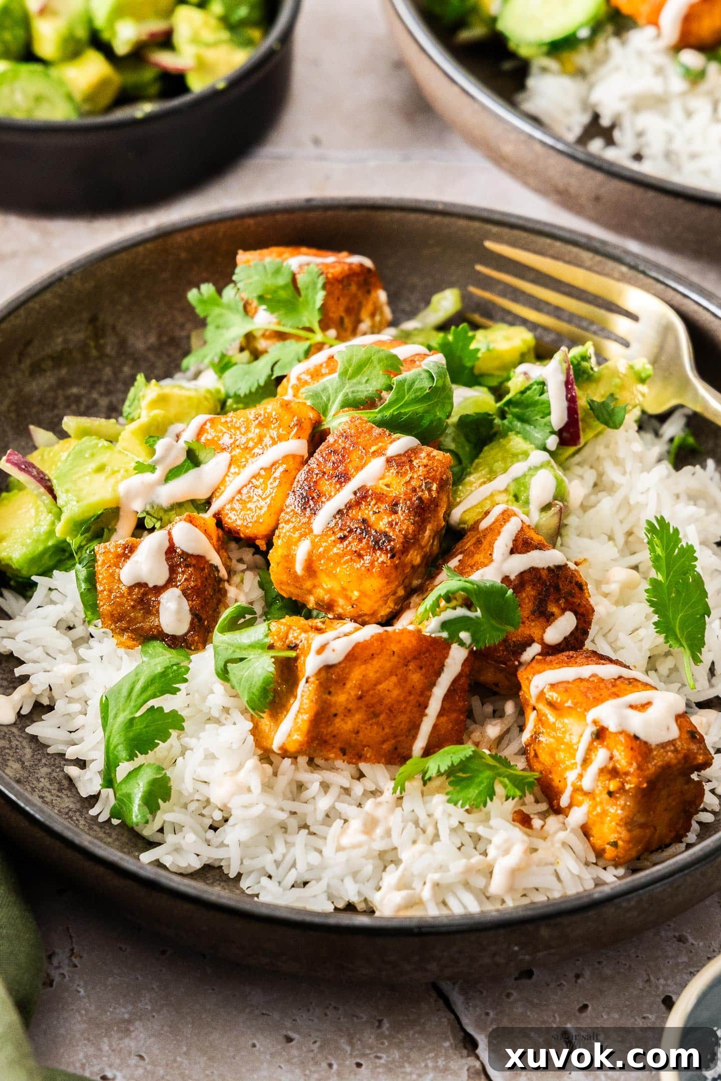 A bowl with rice topped with crispy salmon bites and pieces of coriander.