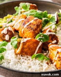 Closeup of crispy salmon bites on rice drizzled with dressing.