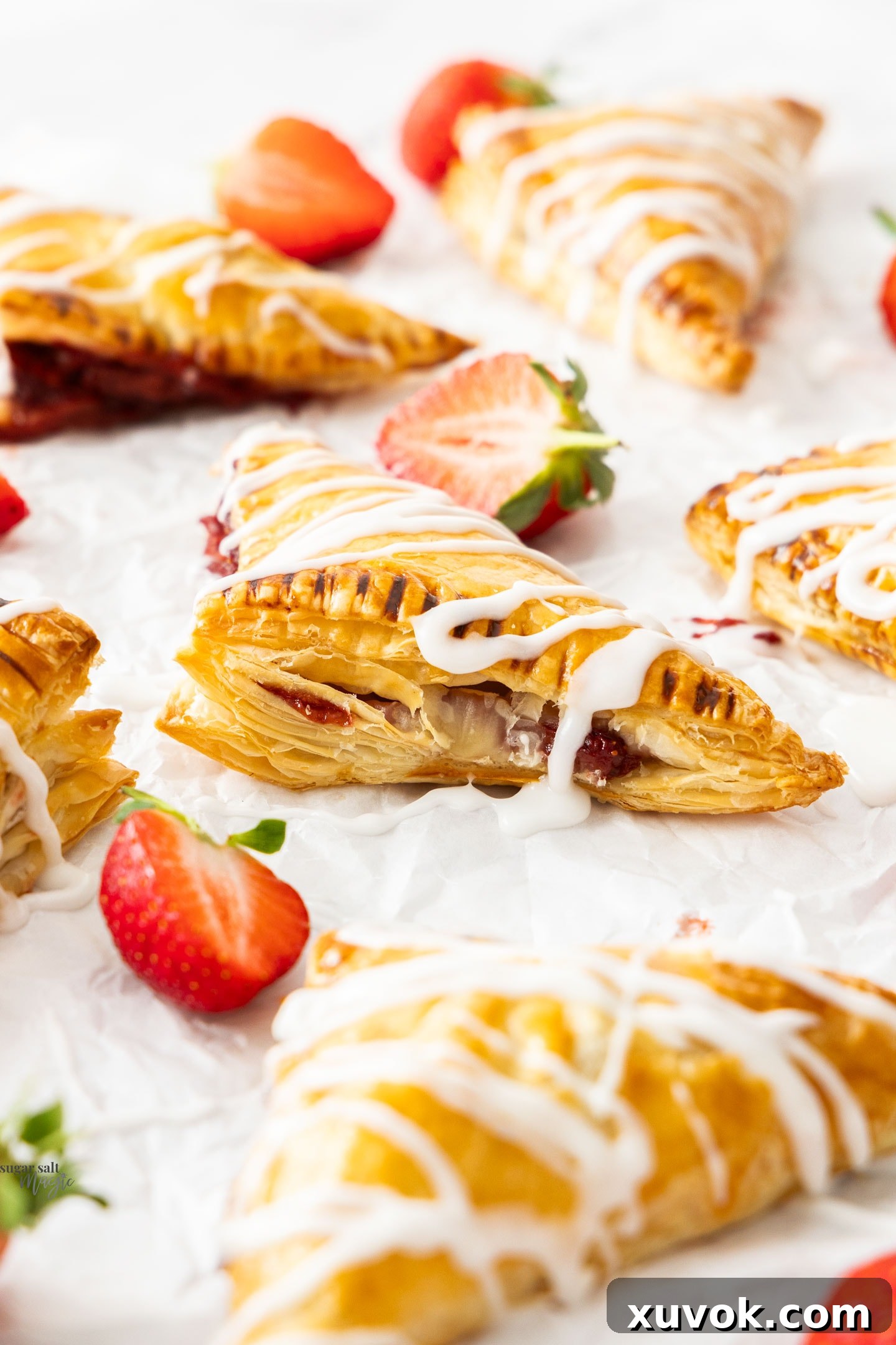 Close-up of a golden-brown puff pastry strawberry turnover, showcasing its beautifully flaky layers and the glistening, inviting texture of the pastry.