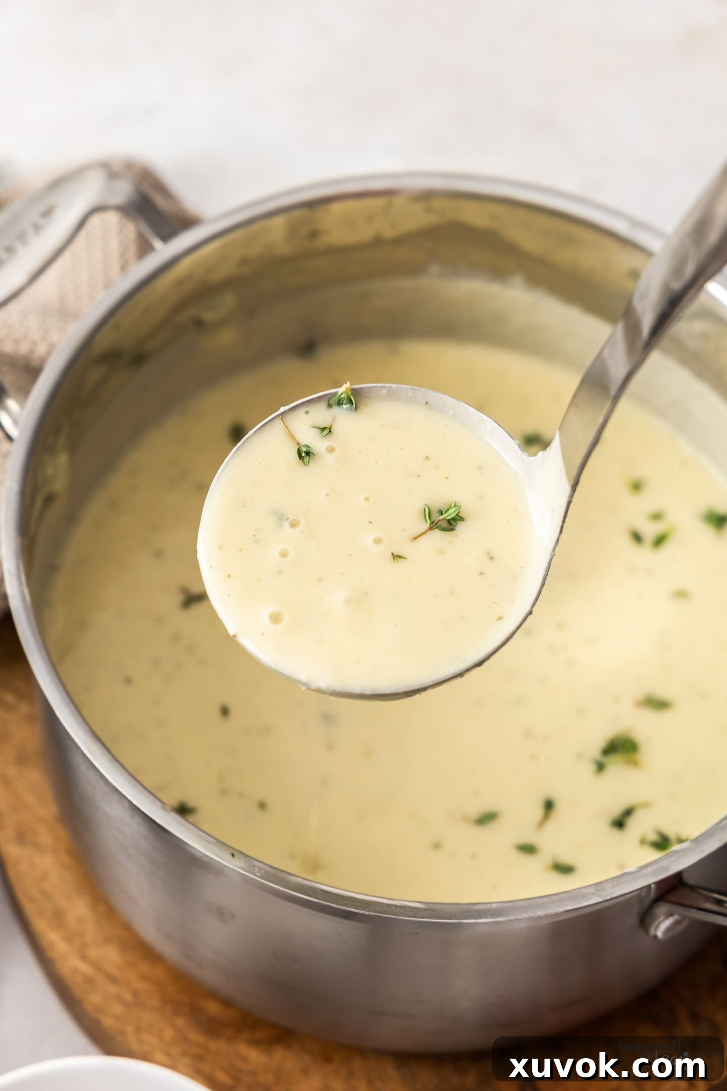 A ladle taking potato chowder from a large pot, showcasing its rich, creamy texture and hearty ingredients.