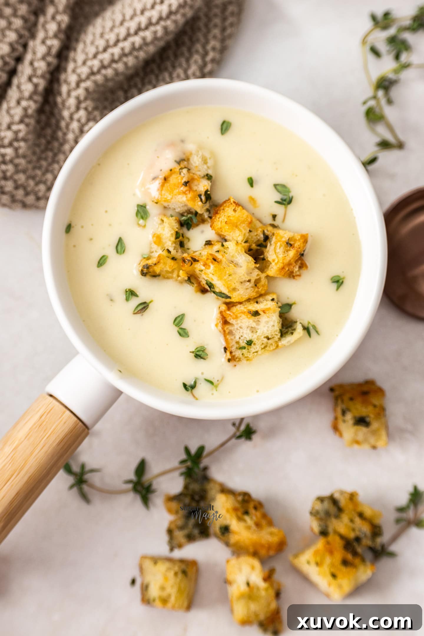 Top-down view of a single soup bowl filled with creamy potato chowder, garnished with fresh herbs and golden croutons.