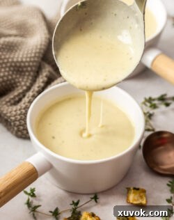 A ladle pouring chowder into a soup bowl.