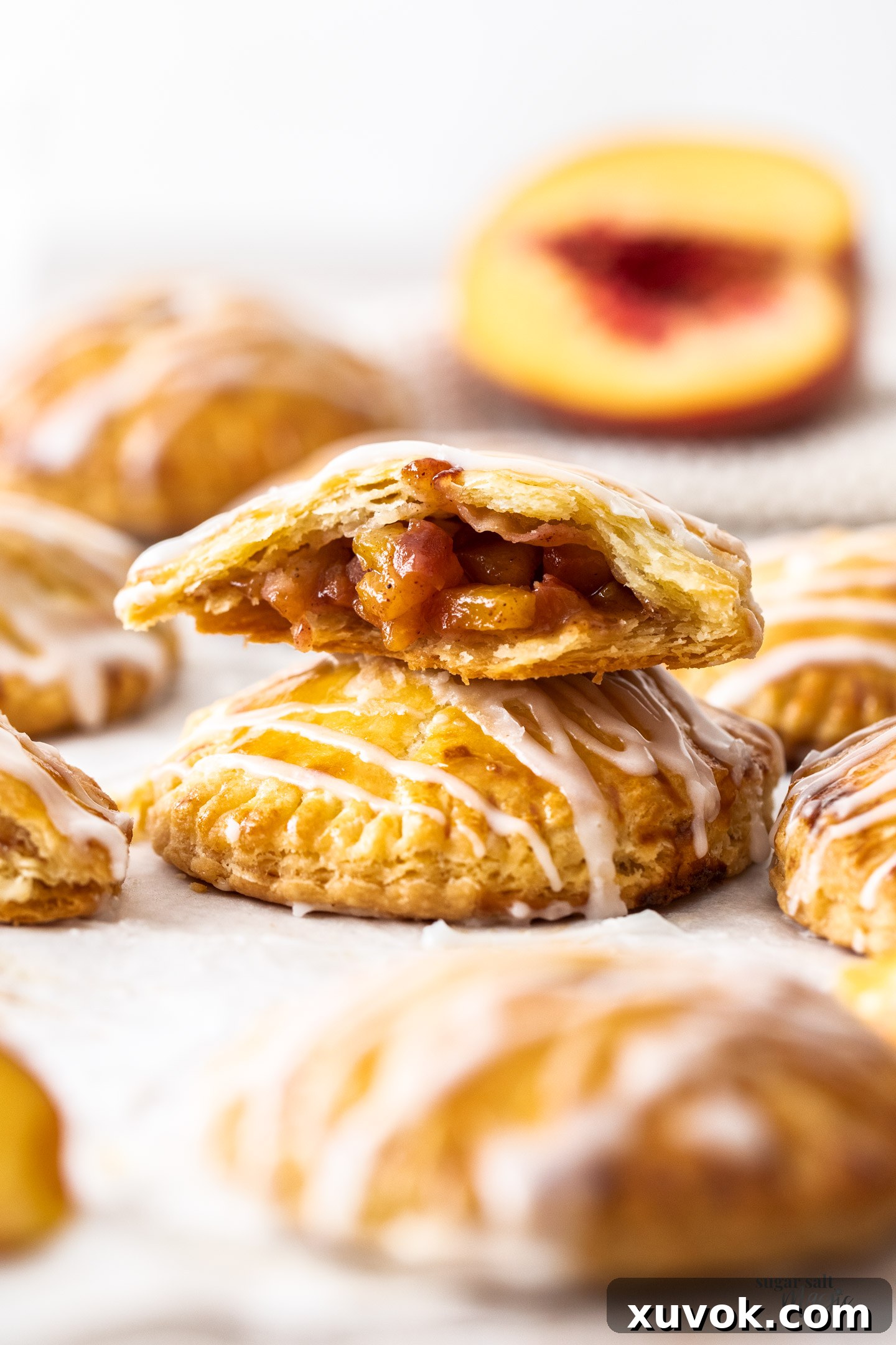 A golden-brown peach hand pie, expertly baked and broken in half, revealing its tender, juicy peach filling nestled within the flaky pastry.
