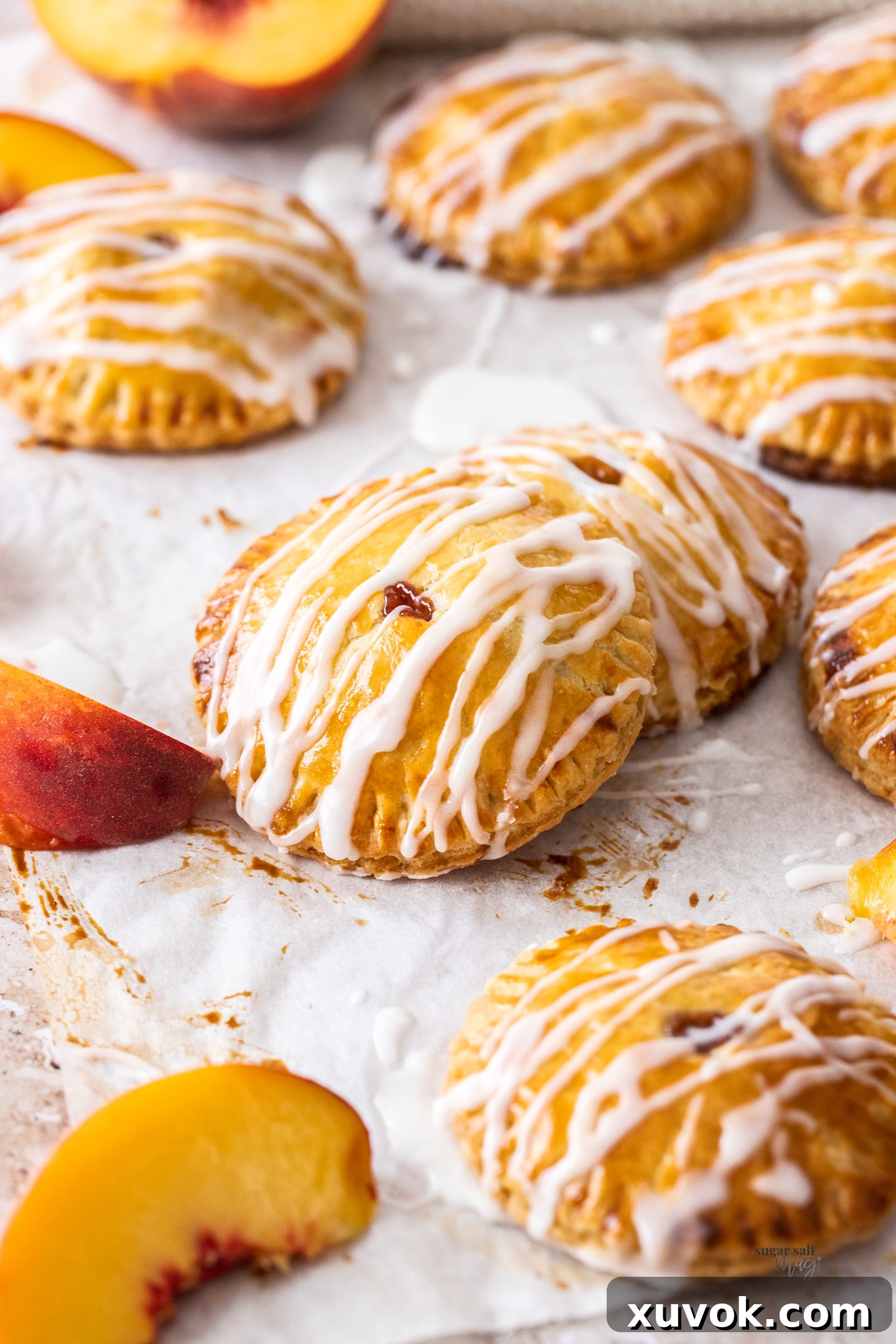 A close-up shot of two peach hand pies, one leaning against the other, showcasing their perfectly crimped edges and golden glaze.