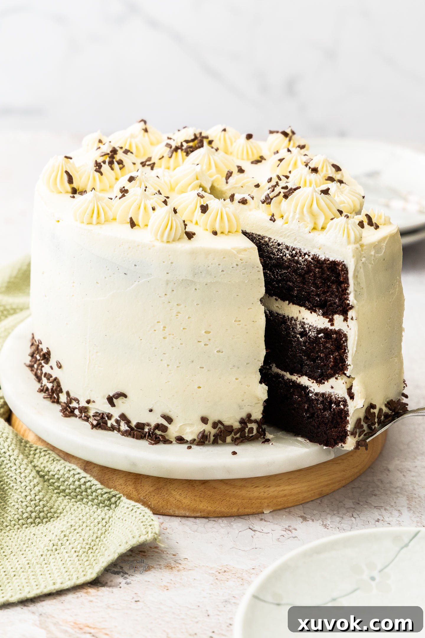 A beautifully decorated whole chocolate cake with fluffy vanilla buttercream, with one slice being gently pulled out to reveal the moist layers.