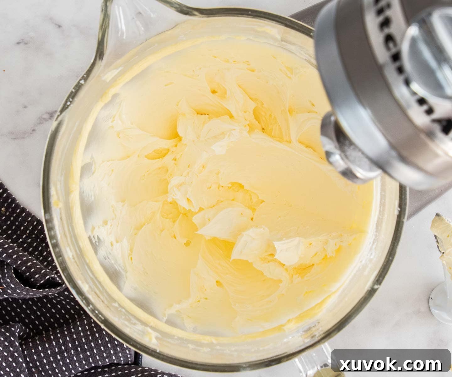 Softened unsalted butter being whipped to a pale, creamy consistency in the bowl of a stand mixer.