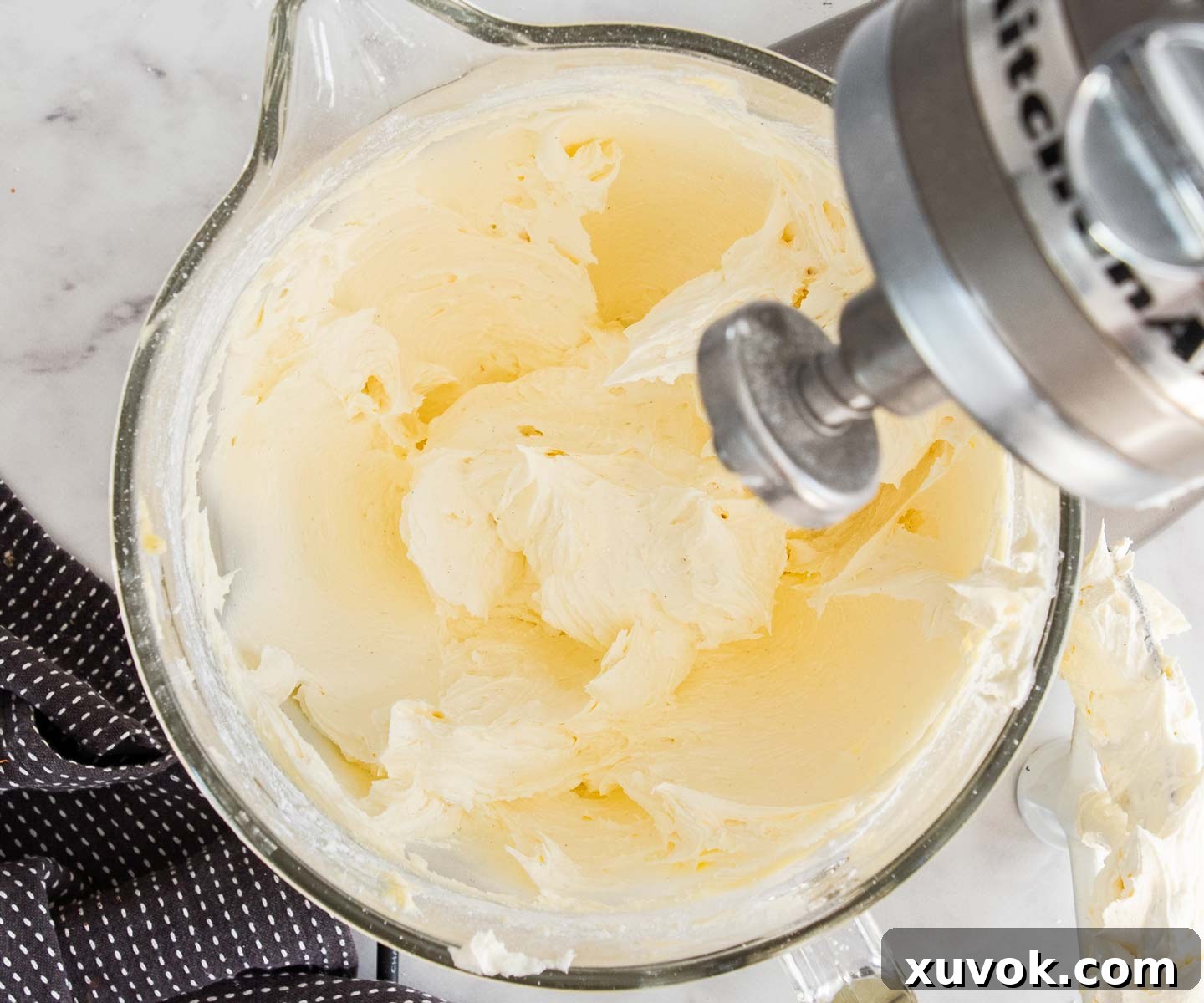 Vanilla buttercream in a stand mixer bowl, showing a smooth and creamy texture after sugar has been added.